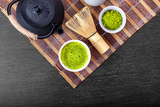 Matcha tea served in ceramic cup with bamboo whisk and teapot. Traditional Japanese ceremony set for relaxation and healthy lifestyle. Organic green powder for beverage preparation
