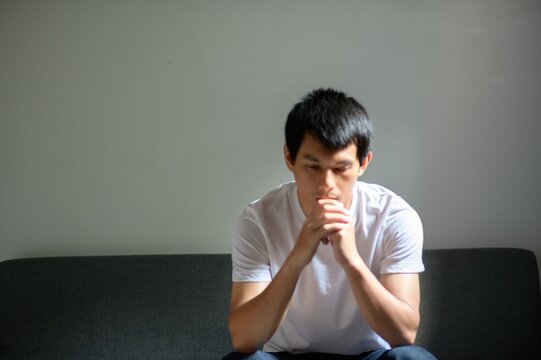 Thoughtful Young Man Sitting on Couch with Pensive Expression
