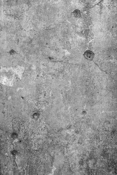 Abstract monochrome grunge background and texture of multiple bullet holes on a rough concrete wall
