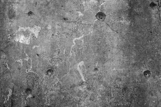 Abstract monochrome grunge background and texture of multiple bullet holes on a rough concrete wall