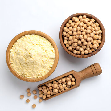 Top view of wooden bowl of gram flour and wooden scoop of chickpeas on white background