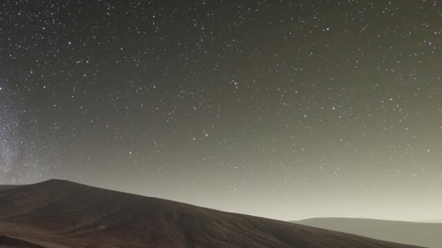 A clear night reveals numerous stars shining brightly over a mountain landscape. The scene captures the vastness of the universe and the beauty of the night sky far from city lights.