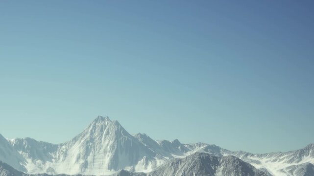 Mountains with snow on their peaks are seen against a bright blue sky. The landscape shows a range of sharp ridges and valleys. This scene captures the beauty of nature in daylight.
