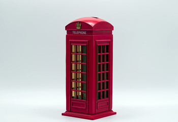 Obraz premium Red miniature london telephone booth piggy bank isolated on a clean white background for savings.