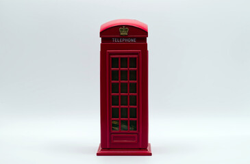 Obraz premium Red miniature model of a classic london telephone booth used as a money box on white background.