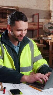 Happy, carpenter or laptop with workshop celebration for shopfitting tender, trade discount or deal. Carpentry, excited man and fist pump at tech for design approval, wood procurement or online order