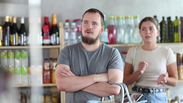 Young woman quarreled with a man in a supermarket. Wife was offended by her husband when buying groceries in the store. 
