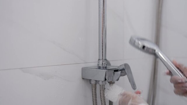 Asian Woman Cleaning Shower Fixture With Brush and Running Water for Bathroom Hygiene