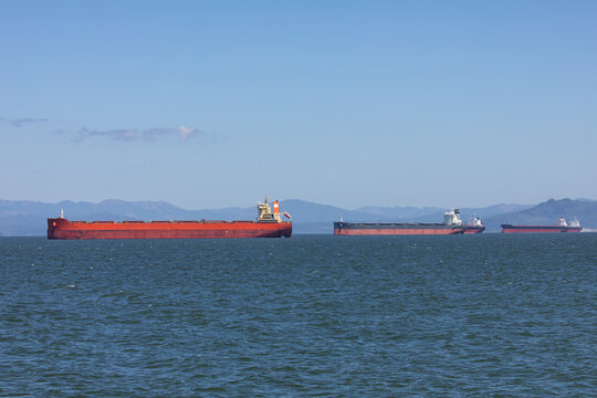 Multiple cargo ships sailing on the Columbia River near Astoria, Oregon, USA, towards the Pacific Ocean, representing global shipping, logistics and international trade