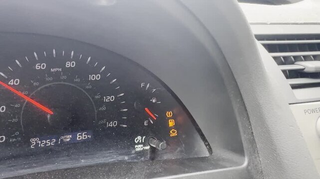 Close-up of a car instrument cluster displaying illuminated check engine, ABS, and tire pressure warning icons.