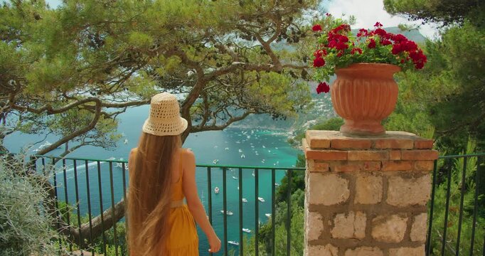 Young woman admiring Marina Piccola bay view from Capri garden terrace in summer