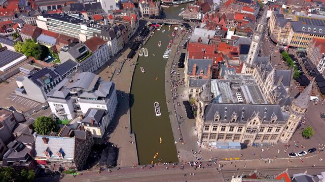 Aerial high angle panoramic view looking down over a scenic river canal with tour boats kayaks pedestrian waterfront embankments and the old post office clock tower under a summer sky