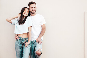 Smiling beautiful woman and her handsome boyfriend. Woman in casual summer jeans clothes. Happy cheerful family. Female having fun. Sexy couple posing in the street near wall. © halayalex