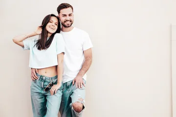 Smiling beautiful woman and her handsome boyfriend. Woman in casual summer jeans clothes. Happy cheerful family. Female having fun. Sexy couple posing in the street near wall. © halayalex