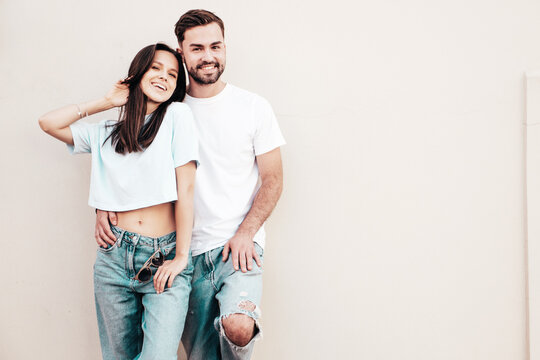 Smiling beautiful woman and her handsome boyfriend. Woman in casual summer jeans clothes. Happy cheerful family. Female having fun. Sexy couple posing in the street near wall.