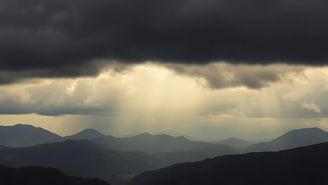 Distant mountains under stormy sky with low dark clouds and misty valley.