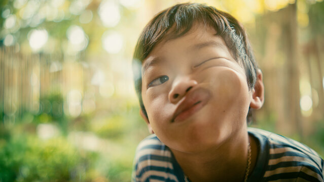 Playful young boy pressing his face against a glass window and making a funny expression. Candid childhood moment filled with joy, humor, curiosity, and authentic family lifestyle.