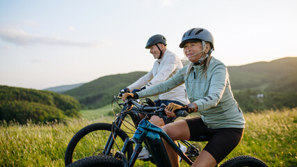 Fototapeta premium Active senior couple exploring nature on electric bicycles