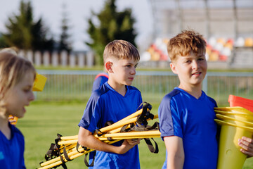 Obraz premium Children helping prepare football training session on sports field.