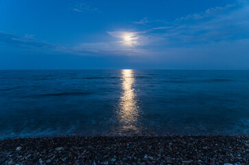 Obraz premium Moonlight reflection on sea water surface at dark beach night
