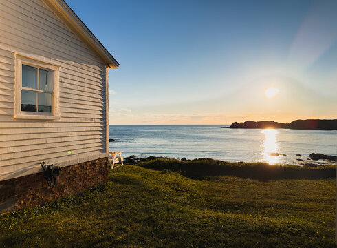 Coastal cottage at sunset over the ocean in Newfoundland
