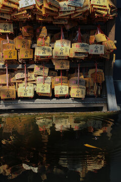 Japanese ema wishing plaques reflected in water