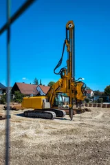 Yellow drilling machine on construction site in Munich, Germany, heavy equipment working on new building ground under blue sky © Natalia Schuchardt