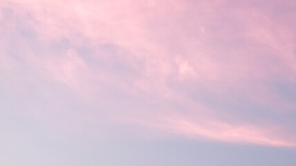 Obraz premium Soft, dreamy sunset sky featuring delicate, wispy pink clouds drifting across a tranquil, pale lilac-blue horizon.