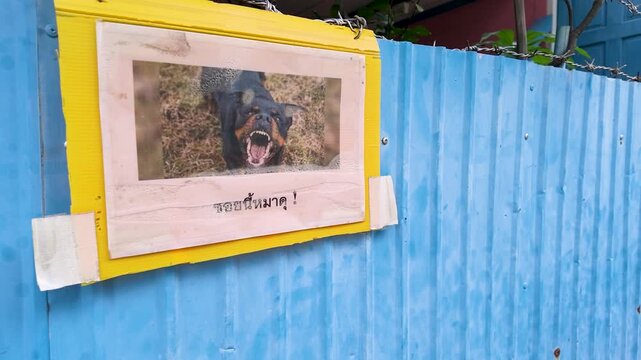 Beware of Dog Warning Sign on Blue Corrugated Metal Fence