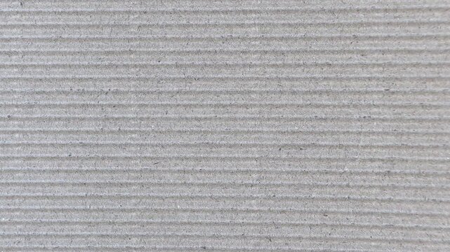 Static close up video of brown corrugated cardboard with horizontal ridges and visible dark fibers. Natural packaging texture background for design, branding and mockups