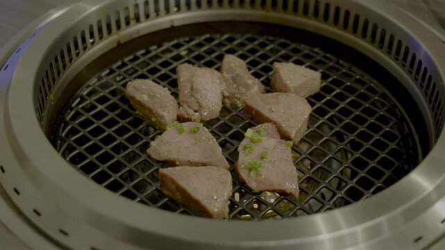 焼肉屋で厚切りのタンを焼いているシーン