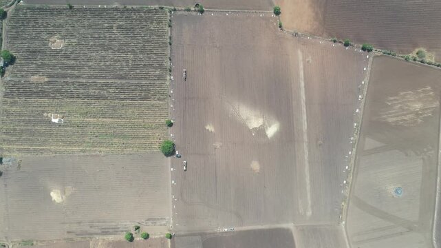 High vertical drone angle framing a large brown dirt plot layout with light sand