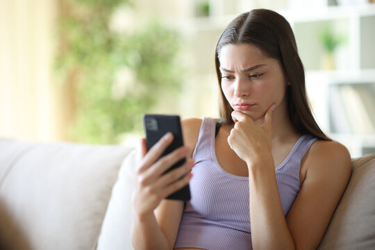 Mistrustful teenage girl watching online content on phone
