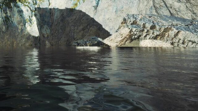 The scene shows water reflecting surrounding rocks and cliffs, with clear ripples on the surface. Light creates shadows on the rocky walls near a body of water.