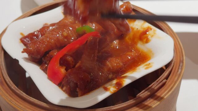 Cantonese Dim Sum Chicken Feet Lifted by Chopsticks in Bamboo Steamer