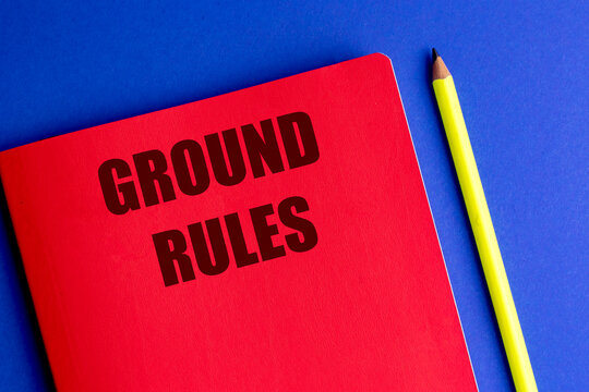 Ground rules text on red notebook with yellow pencil on blue background representing guidelines regulations compliance