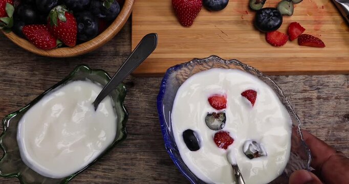 Fruity Strawberry blueberry in wooden bowl Greek style yogurt in glass bowl chopping board knife shopped slice fruit on rustic wooden background Fruit yogurt focus mix move drop keep
