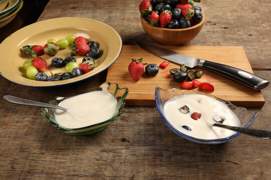 Fruity Strawberry blueberry in wooden bowl Greek style yogurt in glass bowl chopping board knife shopped slice fruit on rustic wooden background Fruit yogurt