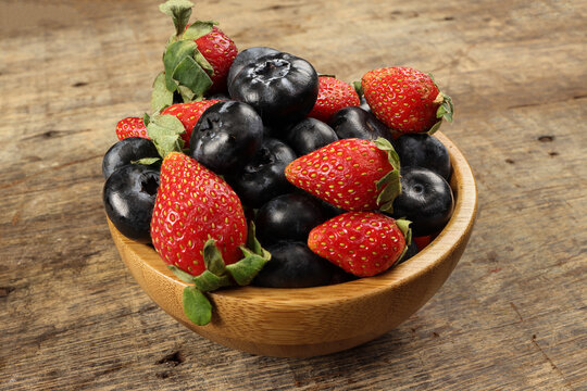 Strawberry blueberry in wooden bowl on rustic wooden background