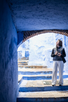 Woman with camera explores alley at Chefchauen