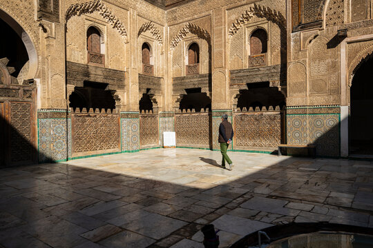 Man walks through ornate sunlit historic courtyard