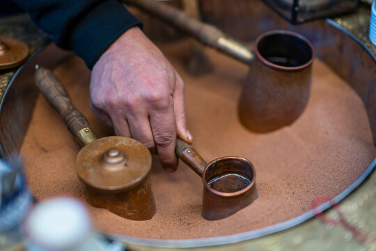 Person brewing traditional Turkish coffee on sand