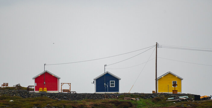 Three colorful houses sit on a remote hill in Newfoundland