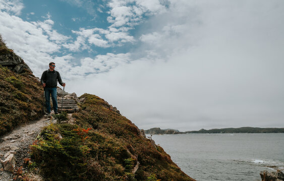 Man hiking along a rugged coastal path in Newfoundland
