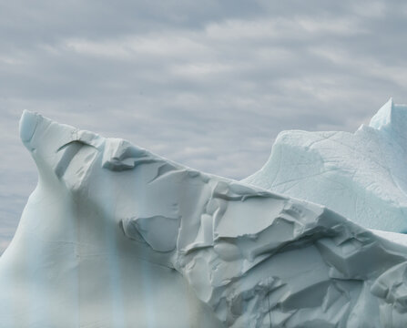 Jagged iceberg peak against a gray sky in Newfoundland, Canada