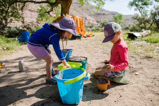 Two young girls playing with mud and buckets at a campsite