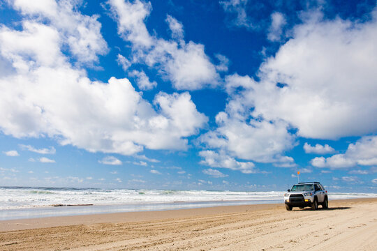 White SUV driving on a remote sandy beach