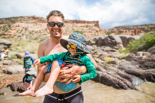 Smiling dad holding his young son at the river