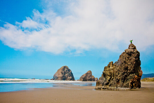 Hiker stands triumphant on a tall beach rock