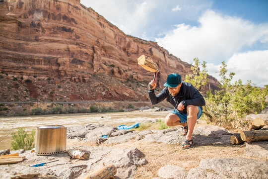 A man splits a log with a hatchet while camping